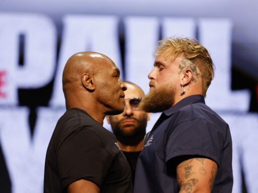 Two men stand side by side, engaged in conversation at a lively boxing event, surrounded by an enthusiastic crowd.